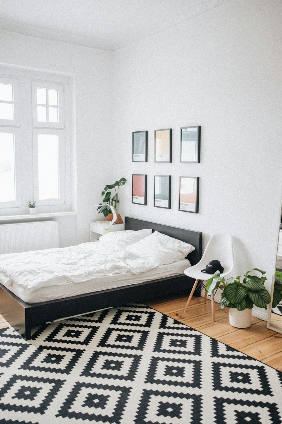 Modern hálószoba növényekkel és geometrikus szőnyeggel.